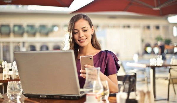 Mujer utilizando un móvil y un portátil