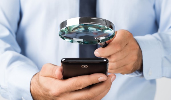 Hombre con una lupa y teléfono móvil